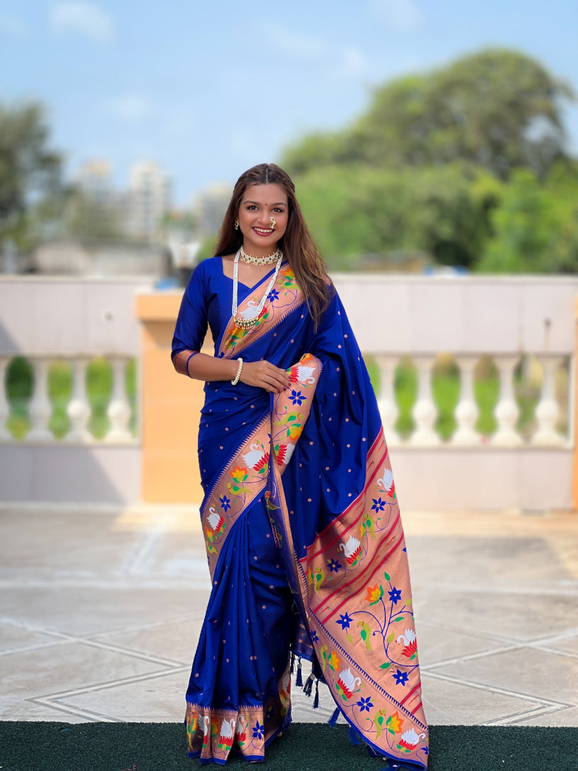 Woman wearing a blue saree with floral patterns outdoors